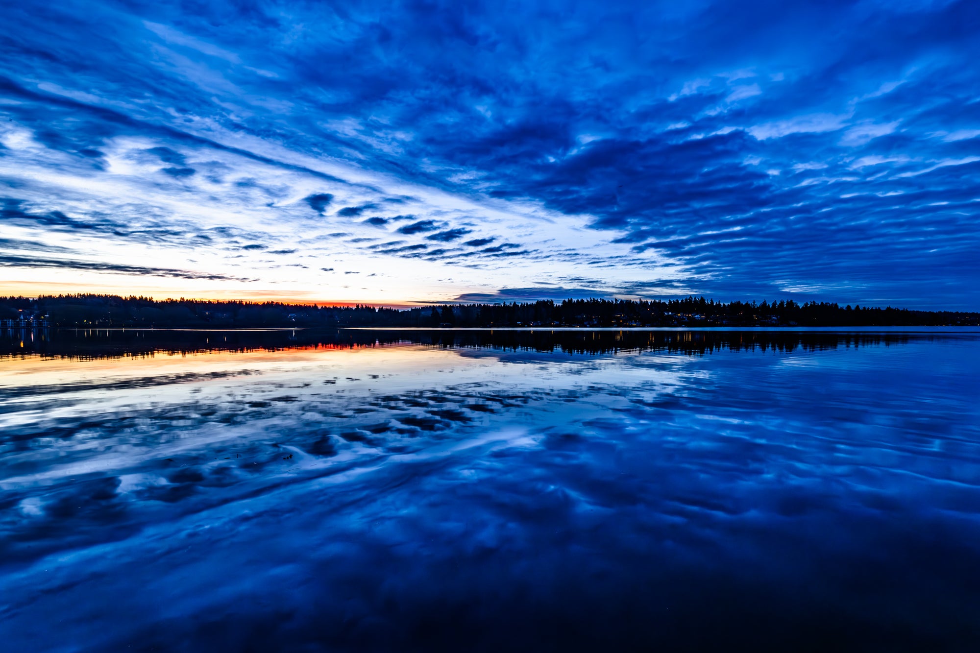 Morning sky over a lake with blue tones and cloud patterns.