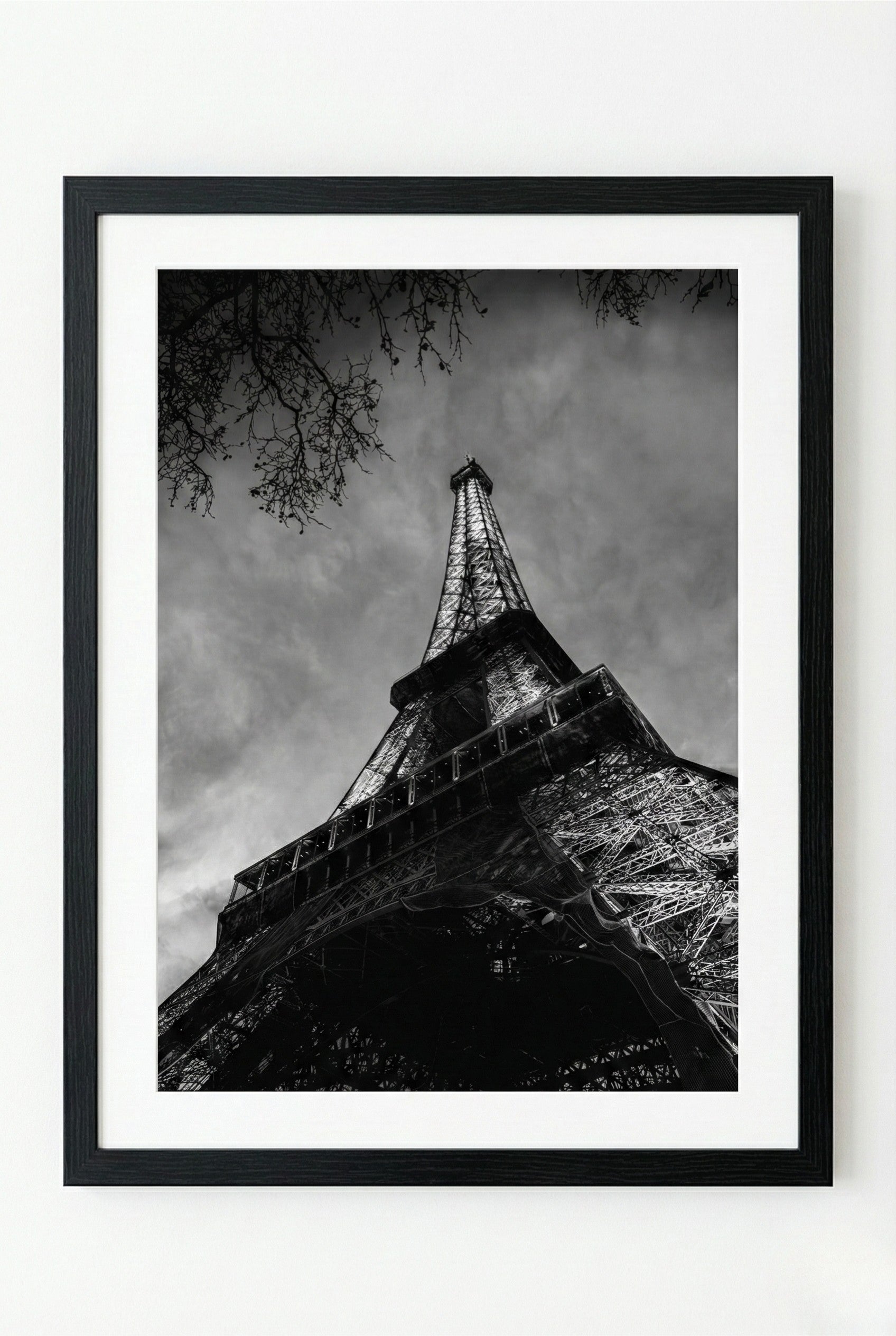 Framed black and white photograph of the Eiffel Tower against a cloudy sky.