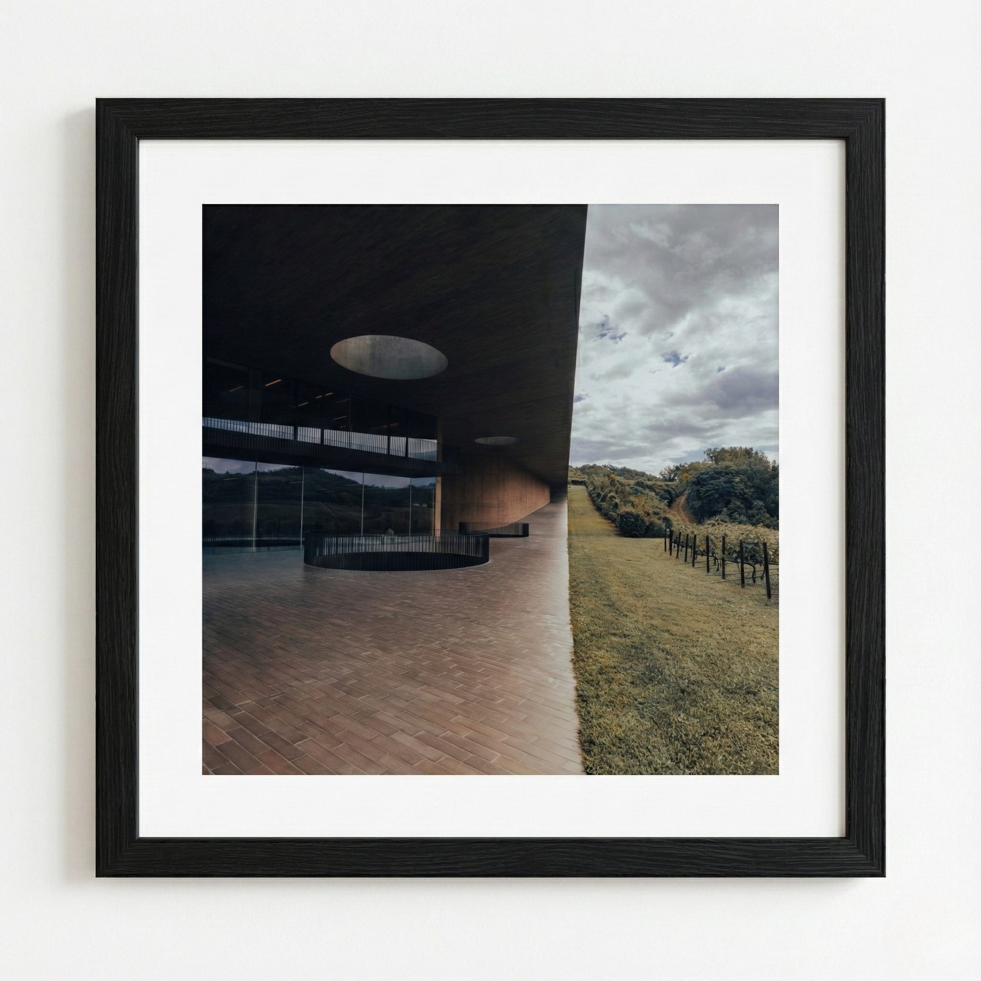Framed photograph of a modern architectural structure with a view of a field and sky.