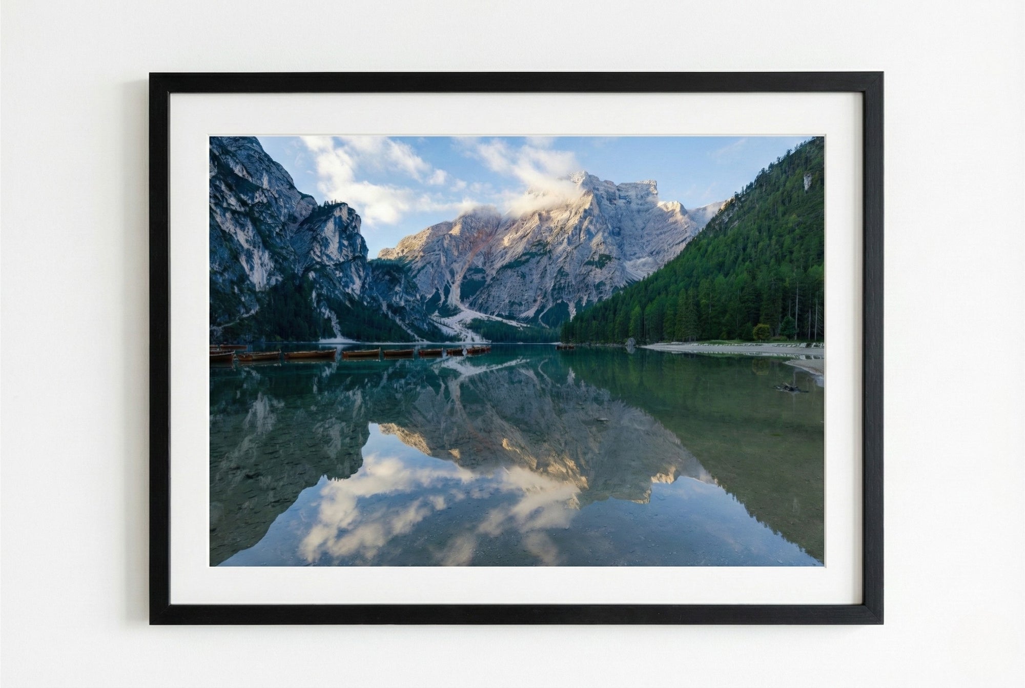 Framed photograph of a mountain lake with a black frame on a white wall