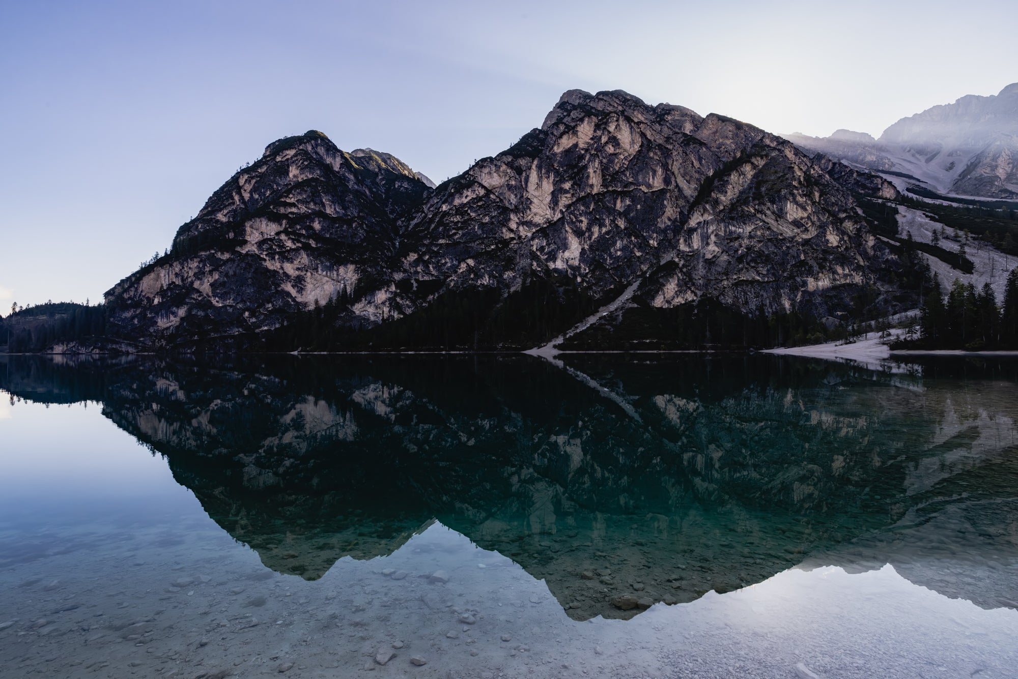 Mountain range reflected in a calm lake with a clear sky.