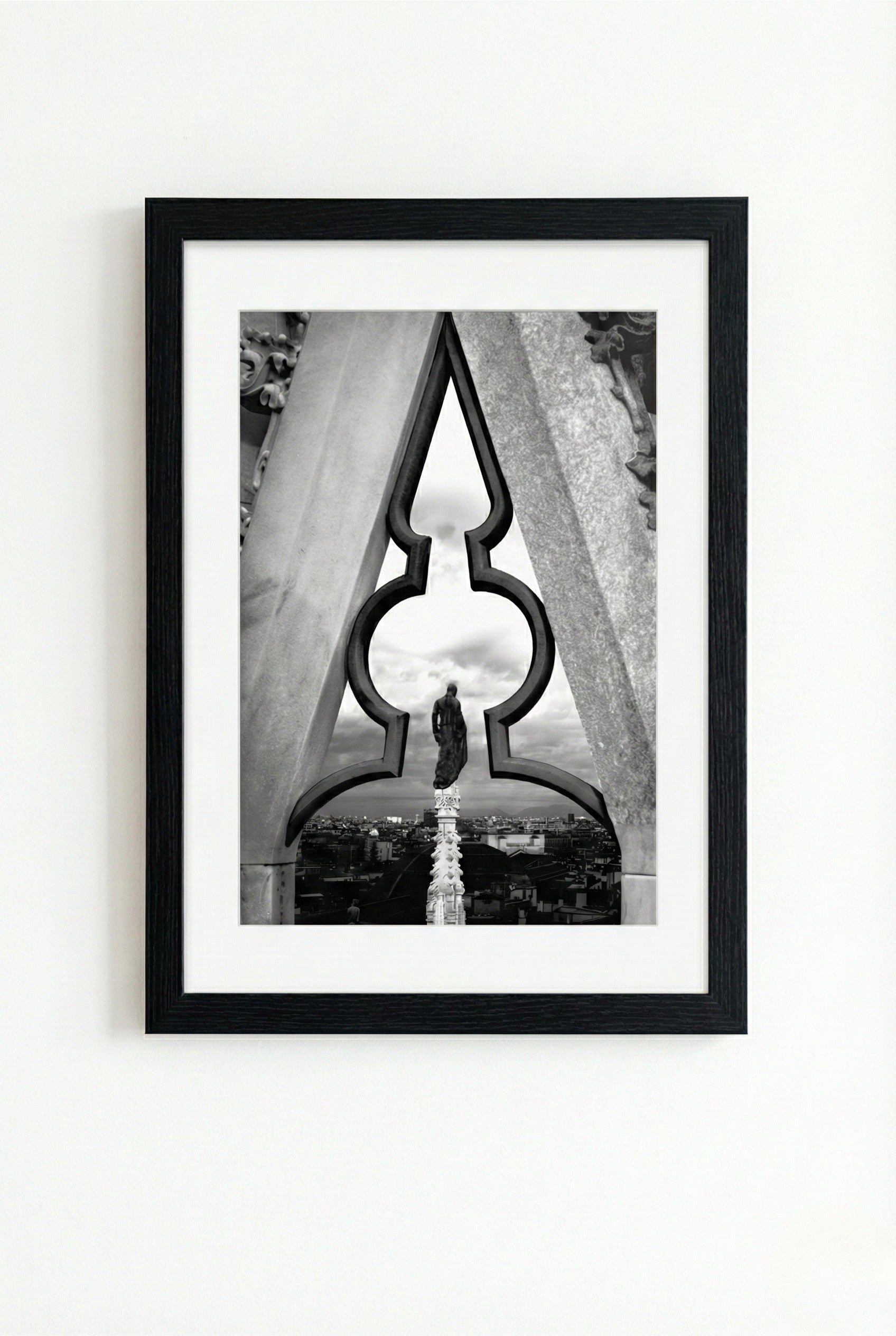 Framed black and white photograph of a person standing in front of a large archway.