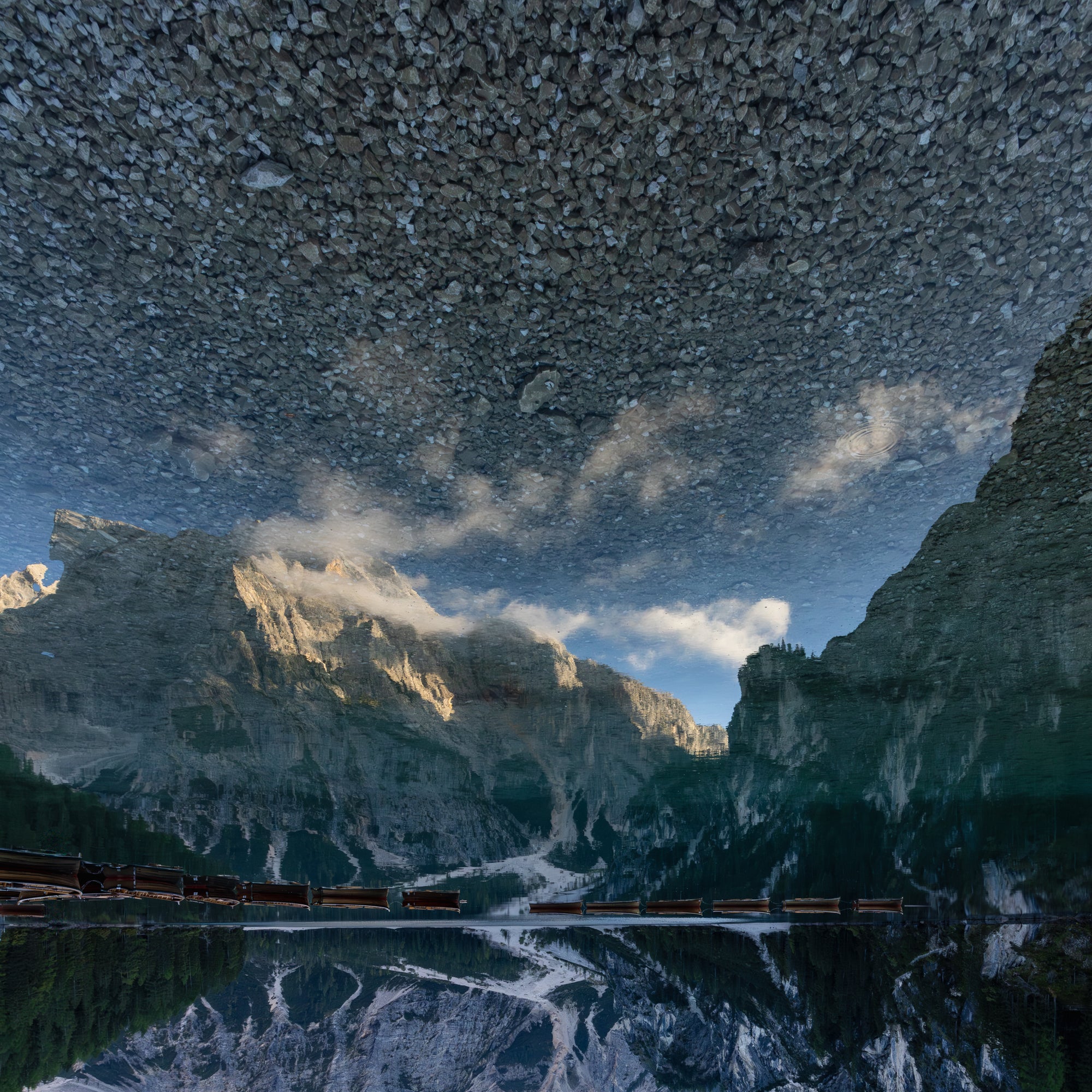 Mountain landscape reflected on the lake with row boats on the water. 