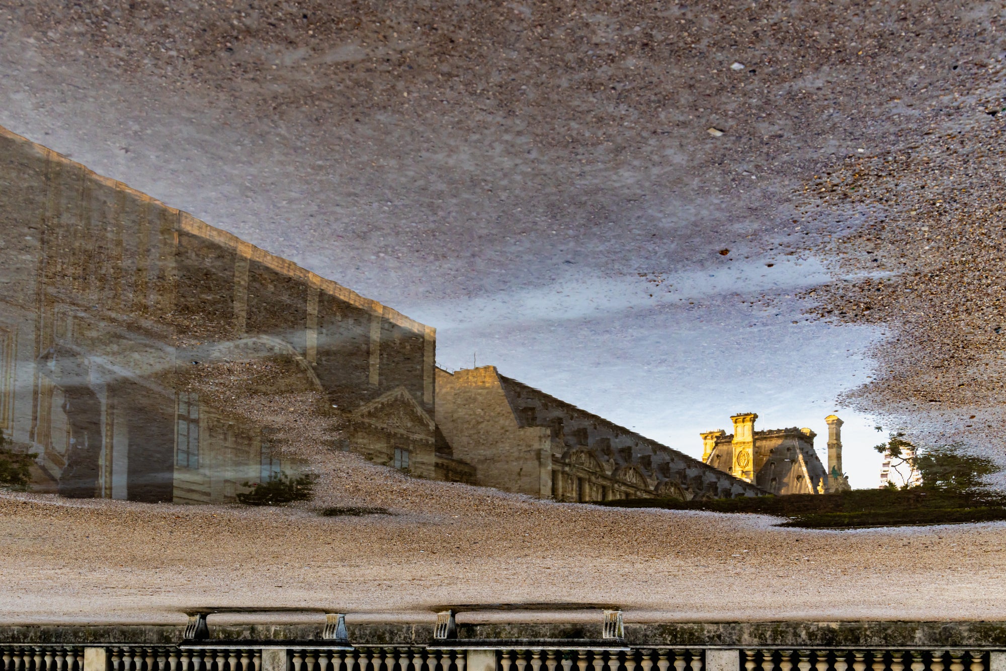 Reflective surface with architectural reflection and sky.