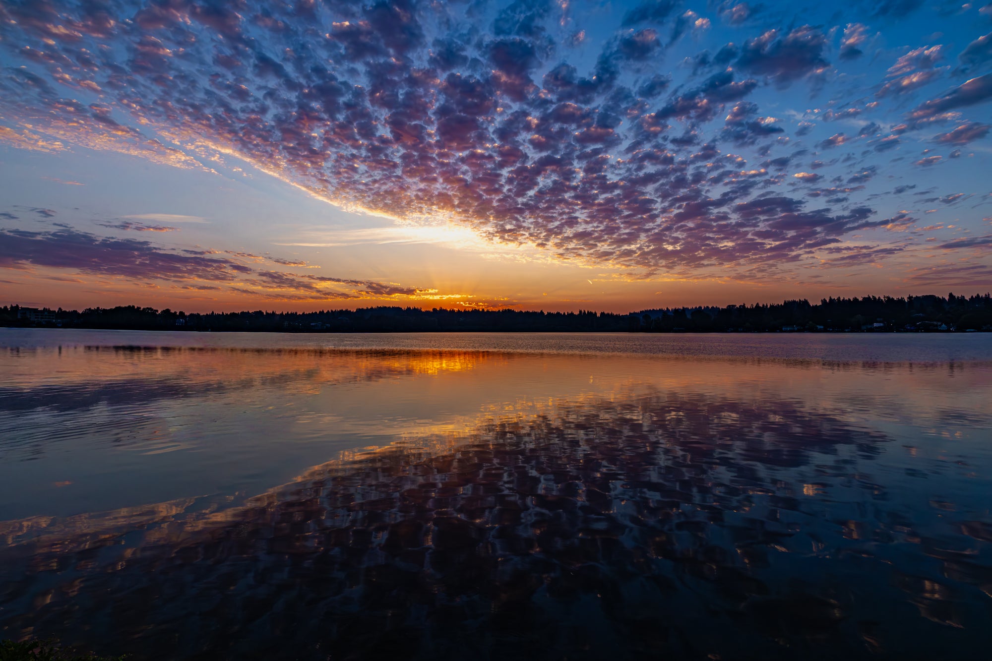 Sunrise over a lake with colorful clouds reflecting on the water