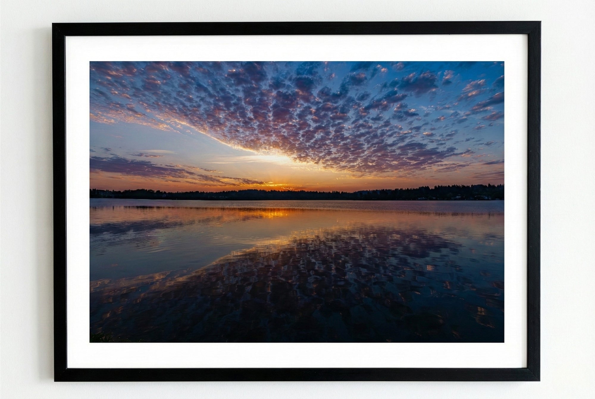 Framed photograph of a sunrise over a lake with a black frame.