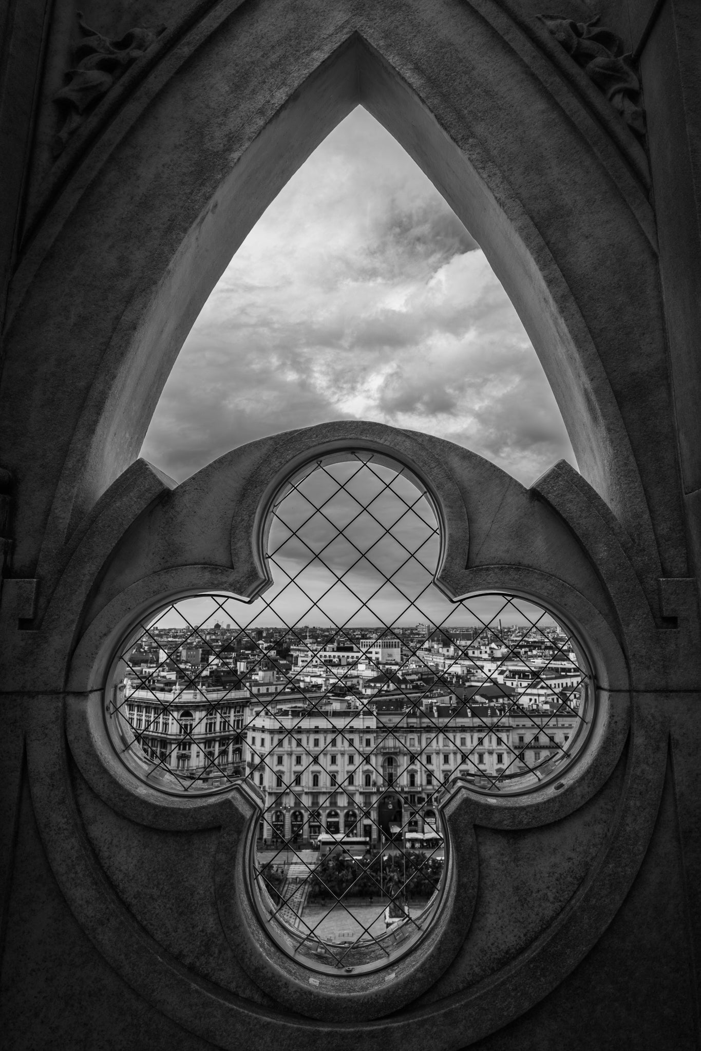 Cityscape viewed through a decorative window with a pointed arch