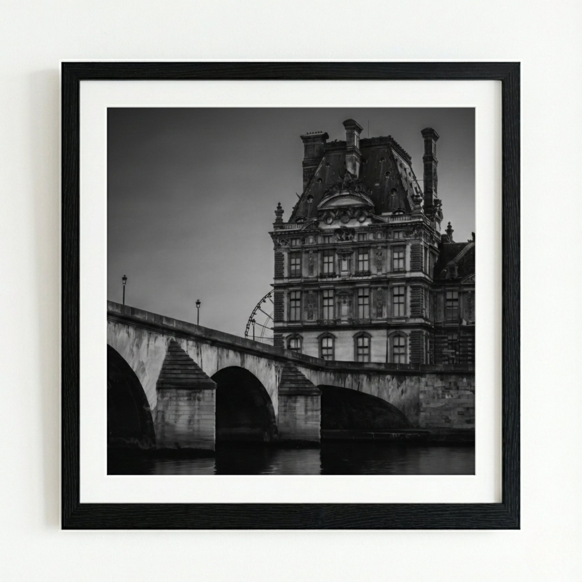 Framed black and white photograph of a building and bridge over water.