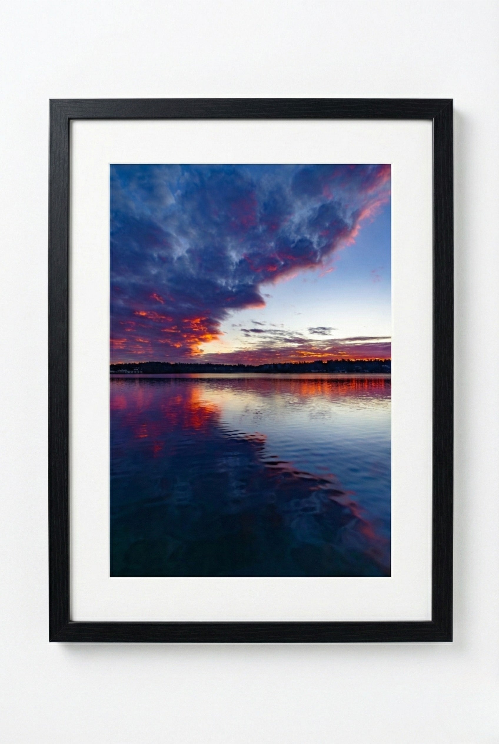 Framed photograph of a sunrise over water with vibrant colors.