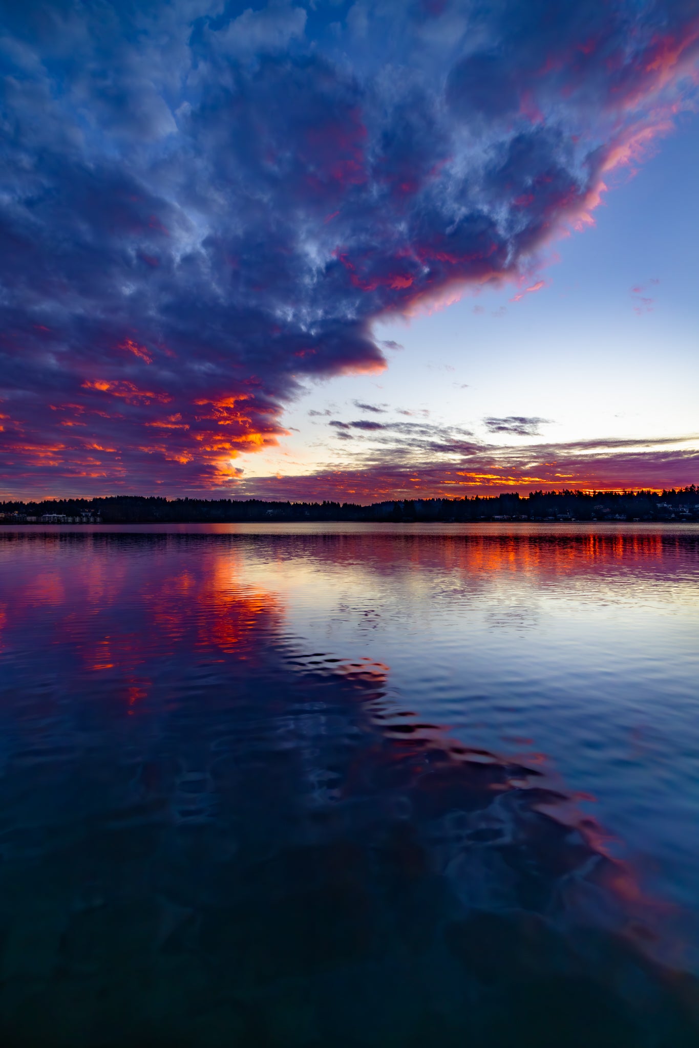 Sunrise over a lake with colorful clouds reflecting on the water